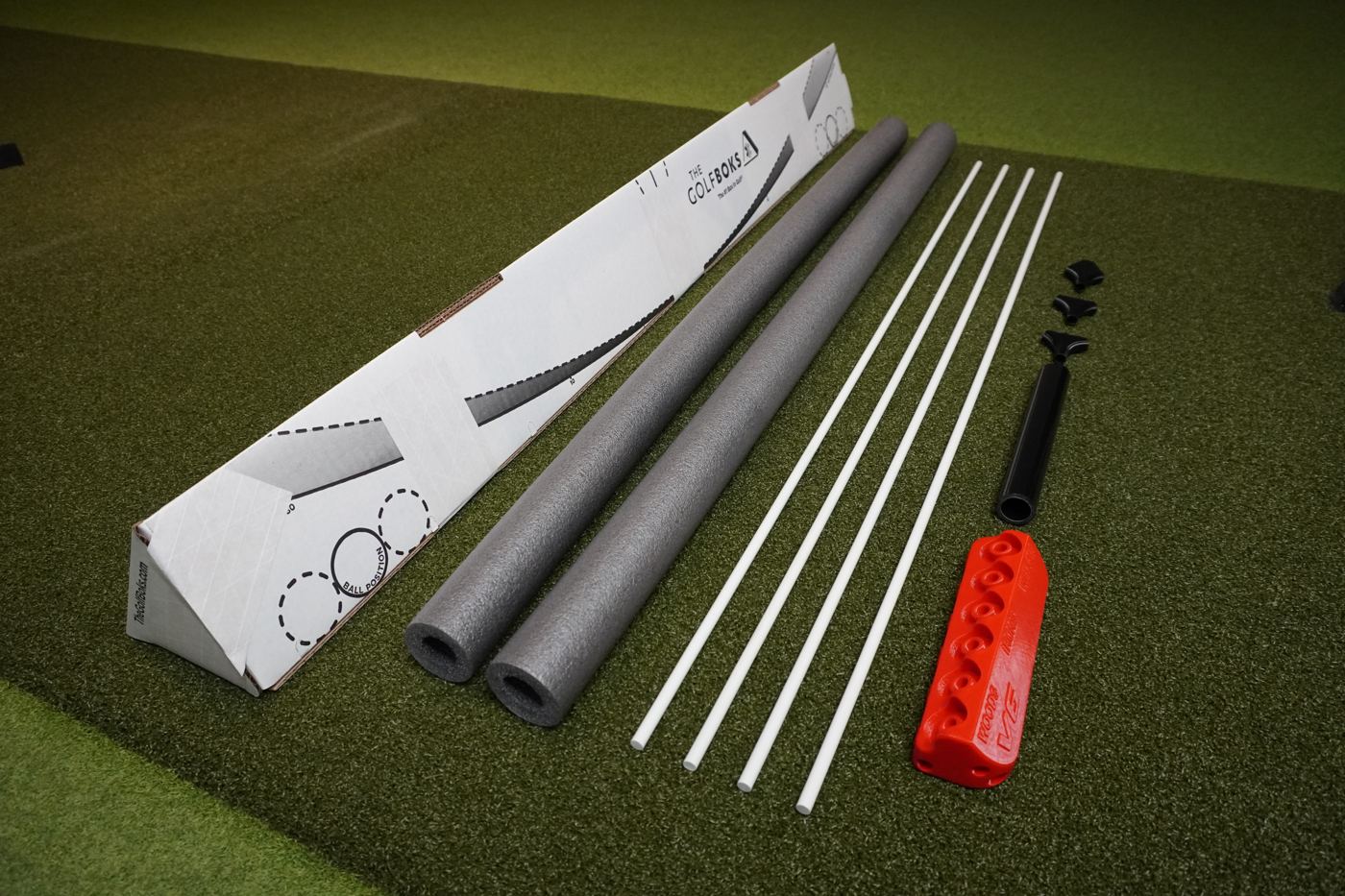 Everything in the box laid out: the Golf Boks 3.0, two foam noodles, four alignment sticks, the V6, the PVC rod and three connectors