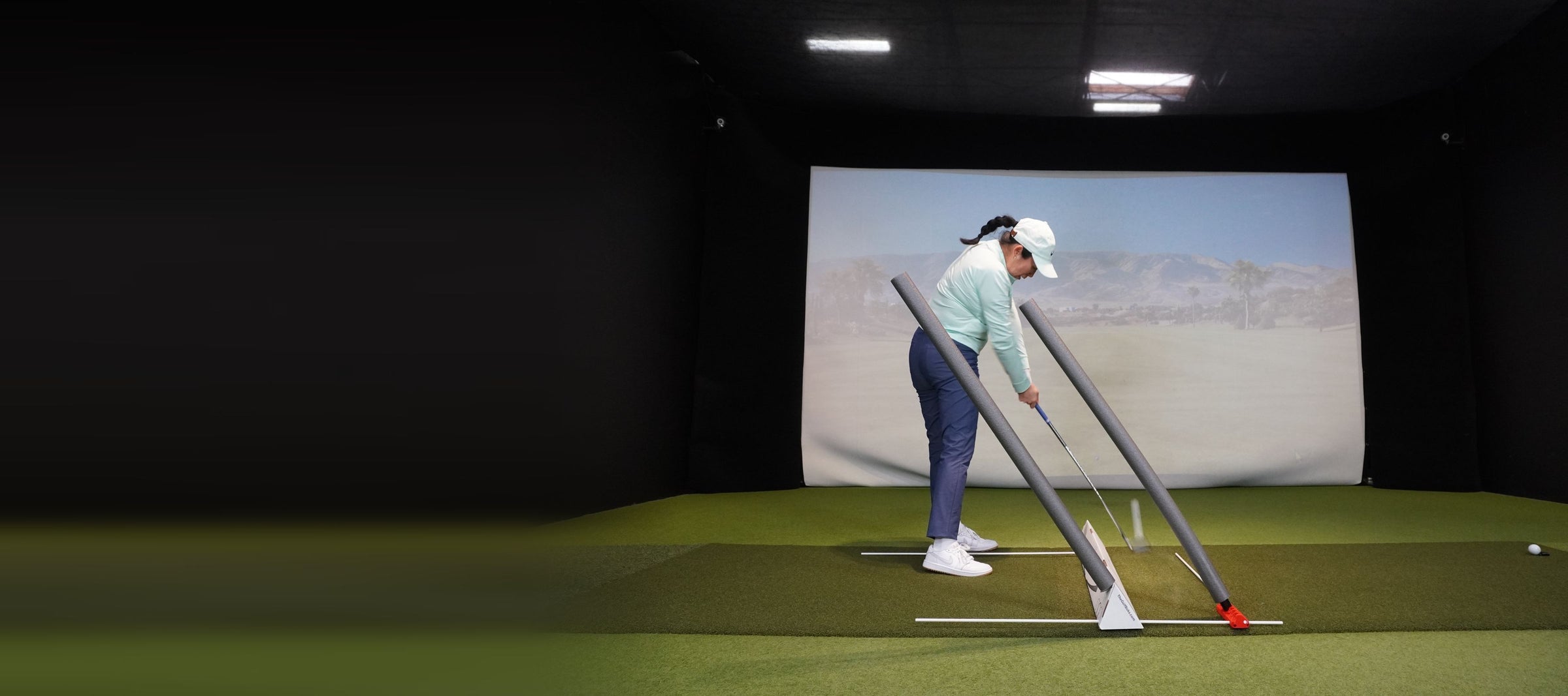 A golfer at address with the V6 and the Golf Boks set up as a two-noodle swing station
